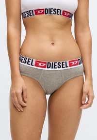 Γυναικεία εσώρουχα Diesel σε αποχρώσεις γκρι με λάστιχο μέσης με μαύρο και κόκκινο λογότυπο. Διαθέτει κλασικό σχεδιασμό brief και απαλό βαμβακερό ύφασμα.
