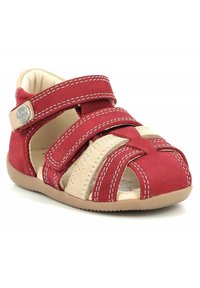 Sándal de punta abierta en rojo y beige con parte superior de ante, tiras de velcro y costuras beige. Suela de goma flexible con agarre texturizado.
