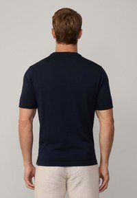 Marineblå kortærmet polo-shirt med klassisk krave, glat tekstur og skuldersømdetaljer. Ren, minimalistisk design.