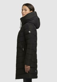 Black puffer coat featuring a high collar, zip pockets, and a branded patch on the sleeve. The design has a quilted texture with horizontal stripes.