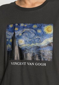 Sort bomulds T-shirt med et grafik af Van Goghs "Stjernesymfoni" med indviklede svævende blå, gule stjerner og en silhuet af et cyprestræ.