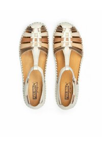 Sandales ouvertes en cuir de couleur crème et bronze métallisé. Elles présentent des brides croisées, des bords cousus et une semelle intérieure rembourrée.