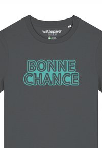 Grijze T-shirt van katoen met een ronde hals. Heeft vetgedrukt, turquoise tekst met de woorden "BONNE CHANCE" op de voorkant.