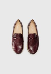 Burgundy leather slip-on shoes with a textured finish, wide band across the upper, and a beige rubber sole.