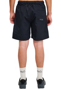 Svarta shorts med resårmidja, bakficka och tryckta "B-583". Bärs med mönstrade strumpor och sneakers.