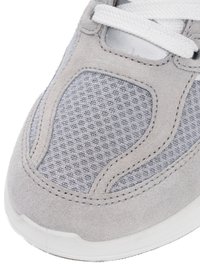 Close-up of gray sneaker toe with mesh fabric, suede overlays, white laces, and white rubber sole.