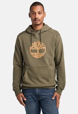 Sudadera verde oliva con un bolsillo tipo canguro y puños acanalados, que presenta un destacado logo de árbol beige en el pecho. Corte casual.