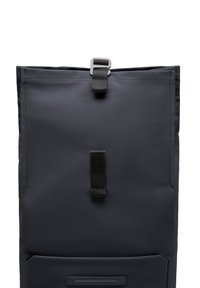 Sac à dos noir à rabat, fabriqué en nylon texturé. Doté d'un clip métallique et de bretelles noires, avec une poche avant pour le rangement.