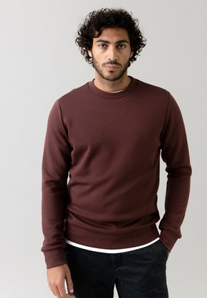 Maroon sweatshirt with a round neckline and long sleeves, made of soft fabric. Features a smooth texture and fitted silhouette.