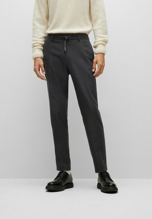 Pantalones grises de corte recto, con una cinturilla ajustable, combinados con zapatos de cuero negros. Textura suave, sin patrones visibles.