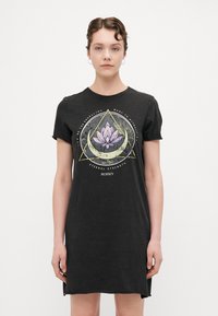 Juodasis medvilnės t-shirt su apvaliu iškirpimu ir trumpomis rankovėmis. Puošia grafika su lotosu, apsuptu geometrinių formų.