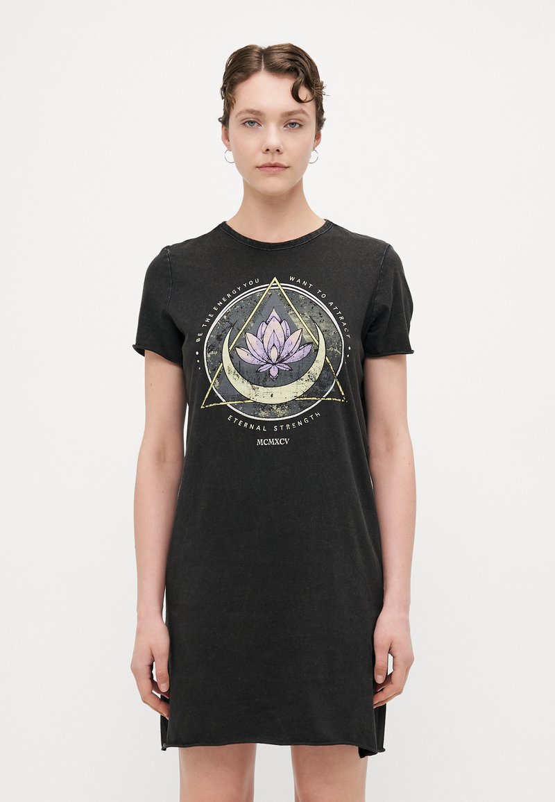 Juodasis medvilnės t-shirt su apvaliu iškirpimu ir trumpomis rankovėmis. Puošia grafika su lotosu, apsuptu geometrinių formų.