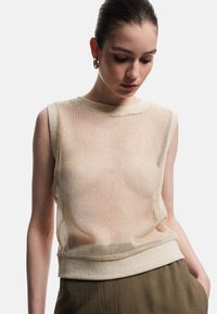 Beige ærmeløs mesh top med ribbet halsudskæring og kant. Letvægts, gennemsigtigt materiale giver en afslappet pasform. Stylet med højresistente bukser.