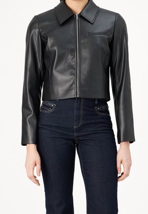Veste en cuir noire cintrée avec fermeture éclair à l'avant, col pointu, manches longues, et jean taille haute bleu foncé.
