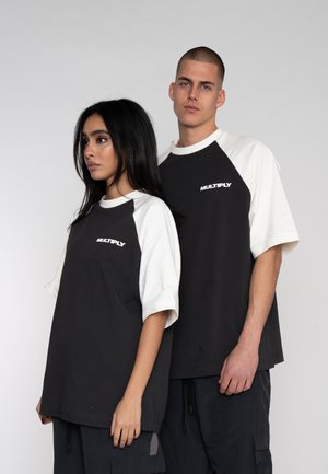 Black and white short-sleeve raglan t-shirts feature a rounded neckline and "MULTIPLY" branding in white. Casual, oversized fit.