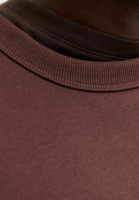 Textile fabric layers arranged, featuring a ribbed neckline, in dark burgundy and black colors with a smooth texture.