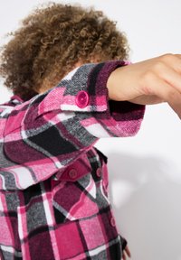 Růžová, šedá a bílá kostkovaná flanelová košile s knoflíkovými manžetami. Má jemnou texturu a velký kostkovaný vzor, který zdůrazňuje syté barvy.