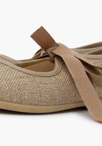 Ballerines en textile tissé de couleur brun clair, avec un bout arrondi et un ruban en tissu assorti noué sur le dessus du pied. Semelle souple.