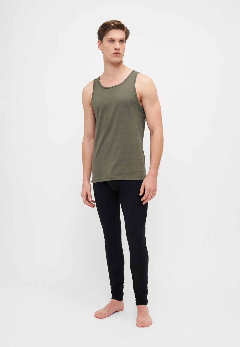 Olajzöld ujjatlan póló, kerek nyakkal, feketére igazított leggings-szel párosítva. Mindkét ruhadarab puha, rugalmas anyagból készült.