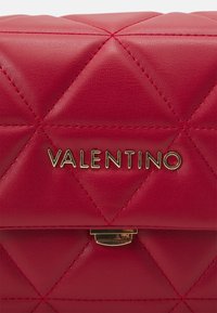 Borsa in pelle trapuntata rossa con logo e chiusura dorati. Il design presenta motivi a rombi con dettagli di cucitura a contrasto.