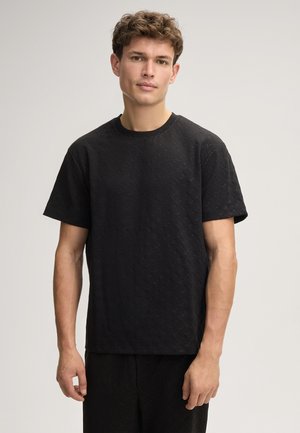 Schwarzes T-Shirt aus strukturiertem Stoff mit Rundhalsausschnitt und kurzen Ärmeln, das ein dezentes Diamantmuster aufweist.