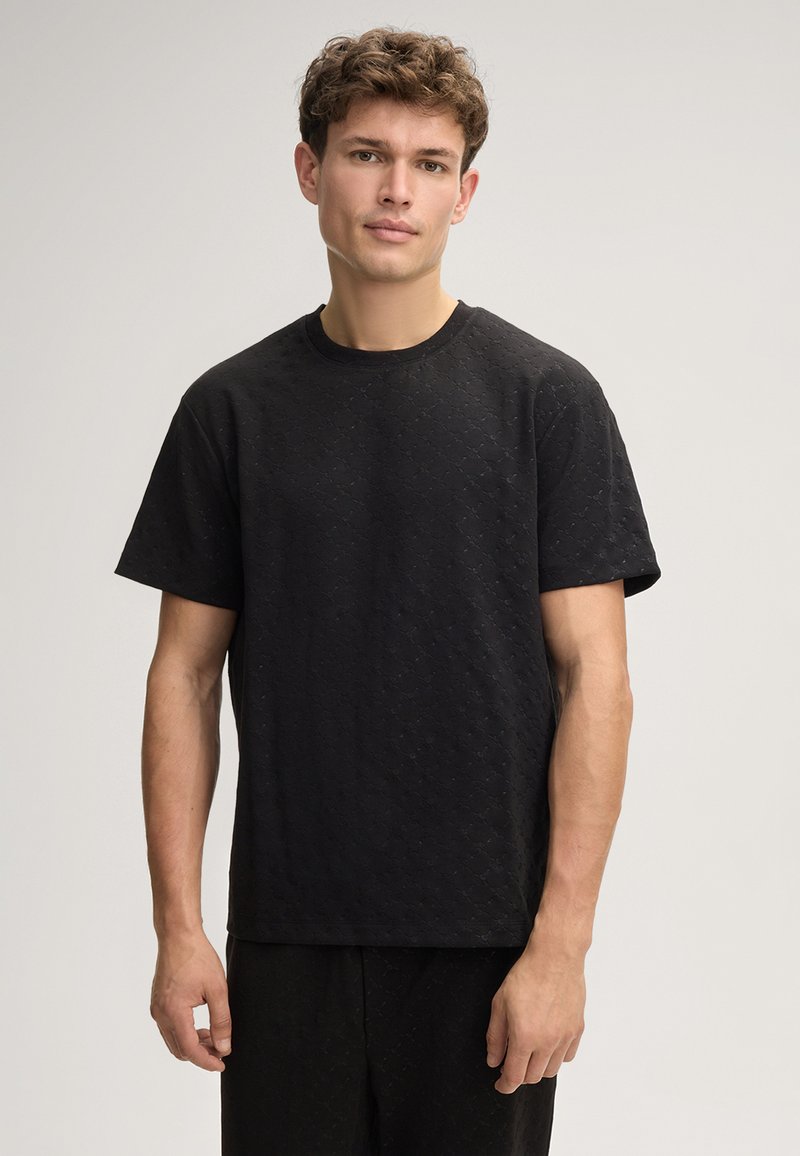 Schwarzes T-Shirt aus strukturiertem Stoff mit Rundhalsausschnitt und kurzen Ärmeln, das ein dezentes Diamantmuster aufweist.