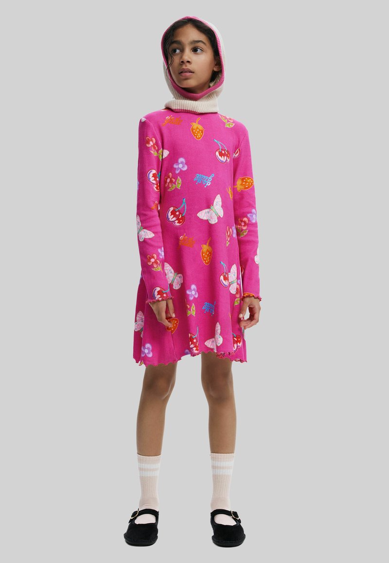 Helles pinkes Kleid mit langen Ärmeln, das mit bunten Frucht- und Schmetterlingsmustern, einem gewellten Saum und einer abnehmbaren Kapuze ausgestattet ist. Tragen Sie dazu knielange Socken und schwarze Schuhe.