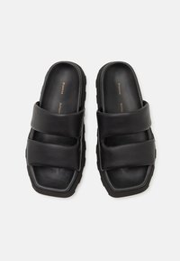 Svarta lädersandaler med två remmar, tjock gummisula och fyrkantig tåform med en mjuk yta.