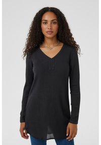 Black long-sleeve V-neck top with ribbed texture and a short placket detail at the neck, paired with blue jeans.