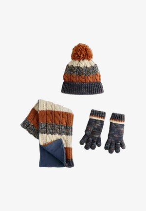 Accessori in maglia per l'inverno: berretto a strisce con pompon, sciarpa abbinata e guanti. I colori includono arancio, crema, blu scuro e fantasie texture.
