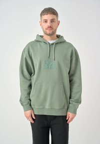 Green hooded sweatshirt made of fabric with a textured finish, featuring a front pocket and embroidered logo in a lighter shade.