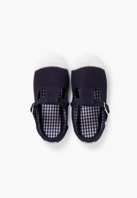Granatowe buty płócienne z białymi gumowymi podeszwami, z otwartym fasonem, regulowanym paskiem i podszewką w kratkę.
