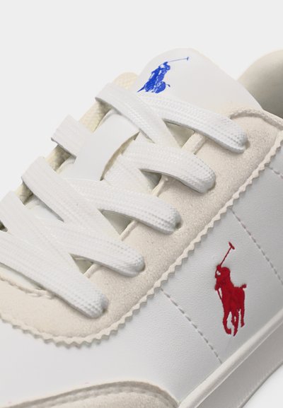 Λευκό αθλητικό παπούτσι με λευκά κορδόνια, με κόκκινα και μπλε λογότυπα παίκτη πόλο στο πλάι και στη γλώσσα, λεπτομερή ραφή και σουέντ λεπτομέρειες.