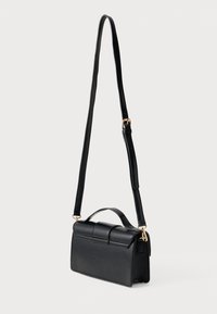 Bolsa crossbody de couro preto com um formato retangular estruturado, uma alça de mão superior e uma alça longa ajustável. Apresenta acessórios em tom dourado.