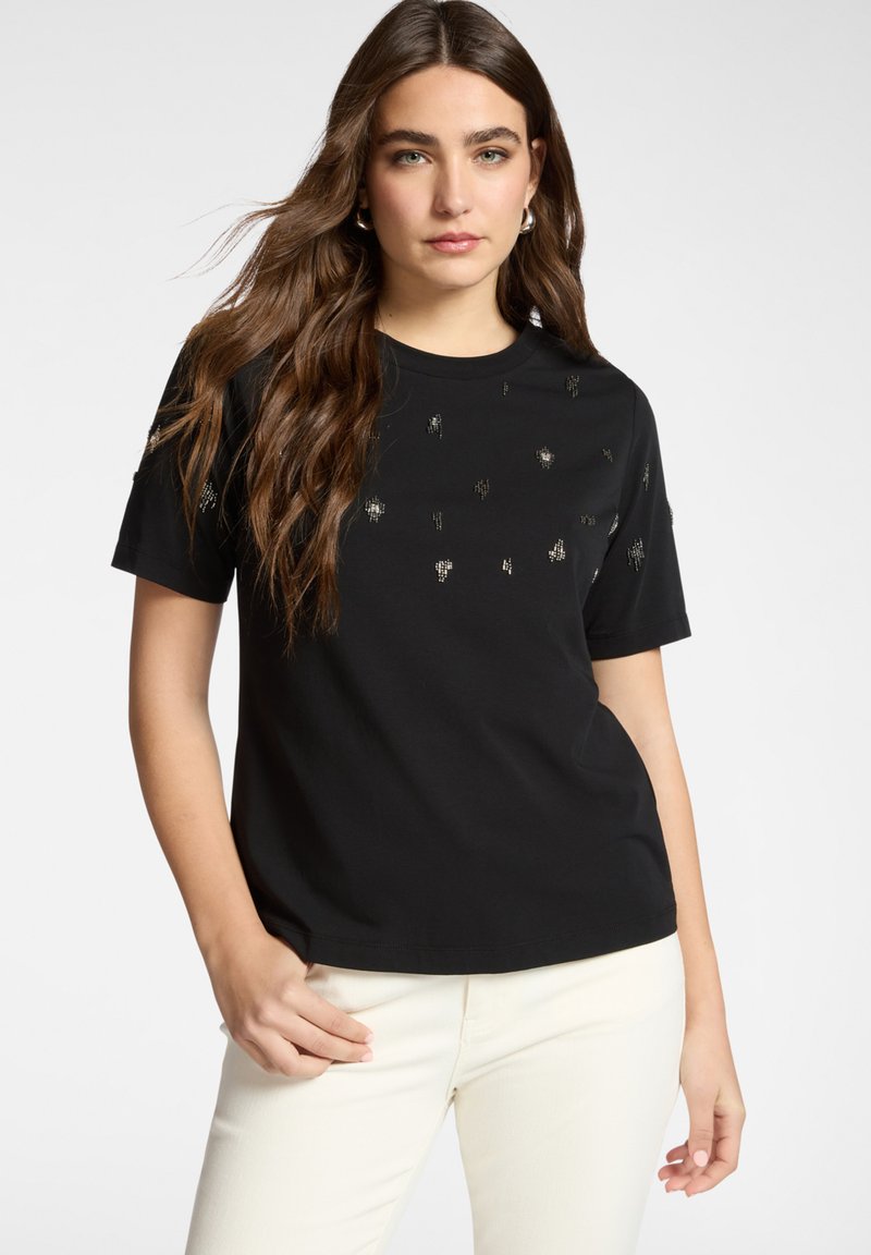 Zwart katoenen T-shirt met korte mouwen, voorzien van verspreide metallic accenten aan de voorkant. Glad oppervlak en klassieke ronde hals.