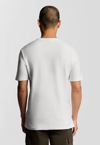 Witte t-shirt met korte mouwen van een textuurstof, ronde hals en een relaxte pasvorm, weergegeven van de achterkant zonder zichtbare logo's of patronen.