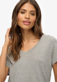 Graues V-Ausschnitt-T-Shirt mit kurzen Ärmeln, aus weichem, strukturiertem Stoff; verfügt über ein kleines gesticktes Logo auf der Brust.
