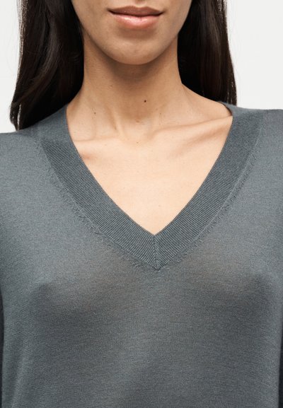 Γκρι πουλόβερ πλεκτής με σχέδιο V-λαιμόκοψη, μαλακή υφή, διακριτική λάμψη και πυκνή πλέξη, που αναδεικνύει τη γραμμή του λαιμού και τις λεπτομέρειες του γιακά.