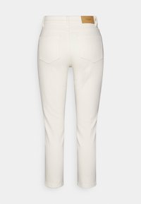 Pantalones de mezclilla blancos con cintura de media altura, diseño de cinco bolsillos y un parche de cuero en la parte posterior. Textura suave con piernas rectas.