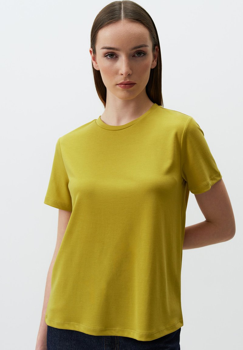 Koszulka z krótkim rękawem, okrągłym dekoltem w oliwkowym kolorze, wykonana z gładkiego materiału o swobodnym kroju i prostym wykończeniu. Minimalistyczny design, bez widocznych logo.
