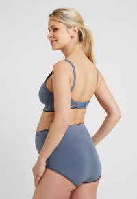 Ensemble de lingerie grise comprenant un soutien-gorge en tissu doux avec des bretelles ajustables et un slip taille haute assorti avec des détails texturés.