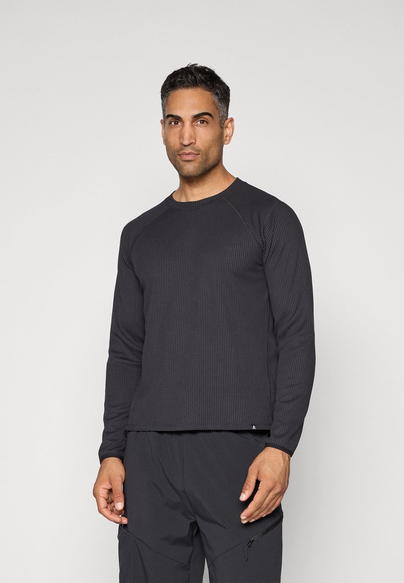 Schwarzes langärmliges Thermoshirt mit geripptem Muster, Rundhalsausschnitt und Raglanärmeln, kombiniert mit dunklen Hosen, vor einem neutralen Hintergrund präsentiert.