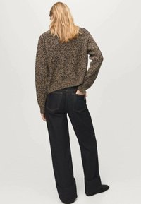 Suéter de punto en marrón y tostado con escote redondo, combinado con vaqueros acampanados azul oscuro con puños doblados y bolsillos traseros.