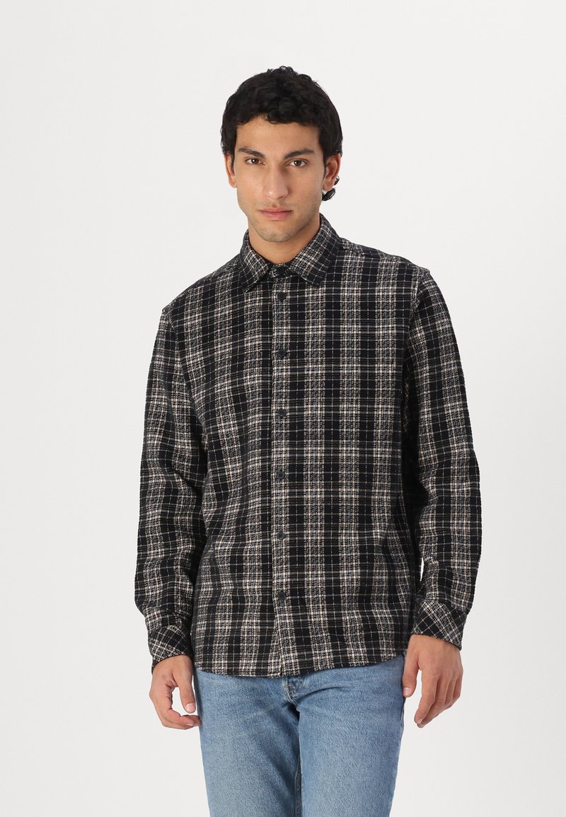 Long-sleeve button-up shirt in black and beige check pattern, made from soft fabric with a classic collar and button front.