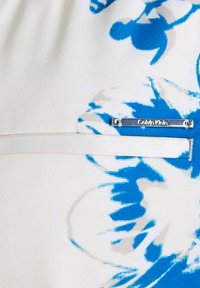 Abito Calvin Klein caratterizzato da un design floreale blu su una stoffa bianca. Include una placca con logo argentato e una finitura leggermente testurizzata.