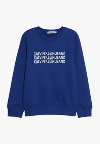 Blå sweatshirt i bomull med ribbade mudd och nederkant. "Calvin Klein Jeans" logotyp tryckt i vitt över framsidan.