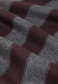 Tkanina wełniana w odcieniach szarości z szerokimi bordowymi paskami, o miękkiej teksturze i subtelnym połysku, ułożona w fałdy, aby ukazać detale wzoru.