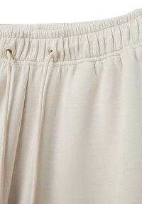 Cintura elastica beige chiaro con cordoncino regolabile; texture del tessuto morbida e liscia; arricciature nella parte superiore per una vestibilità ottimale.