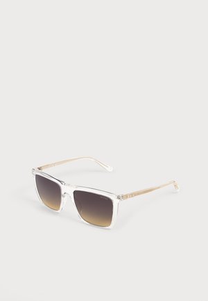 Lunettes de soleil carrées avec monture transparente et branches couleur or, verres dégradés foncés et un logo discret de la marque sur la lentille.