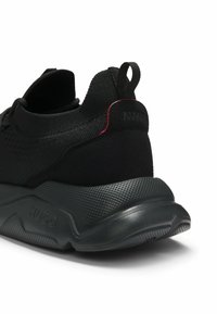 Baskets de sport noires avec semelle texturée, dessus en maille, languette de traction au talon, et "HUGO" embossé sur le côté de la semelle.